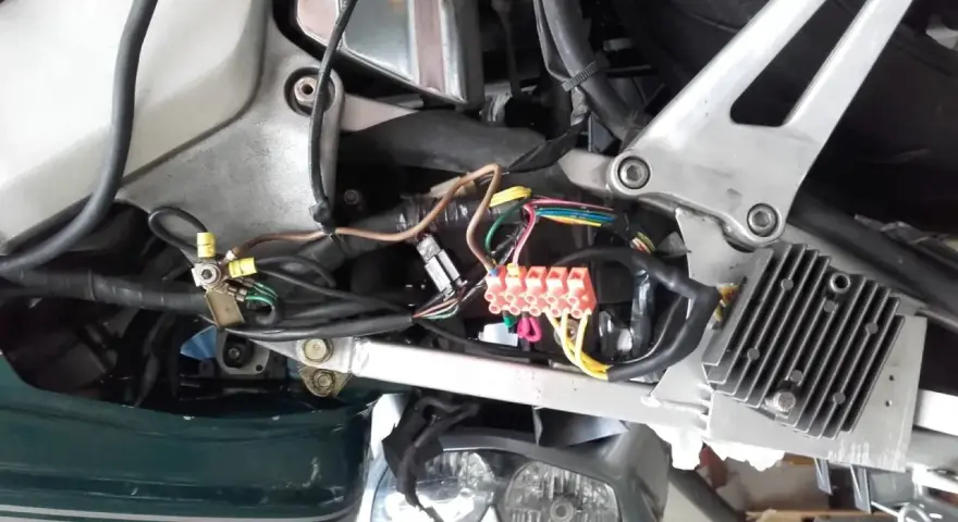 Widok instalacji elektrycznej skutera z widocznymi bezpiecznikami i przewodami.