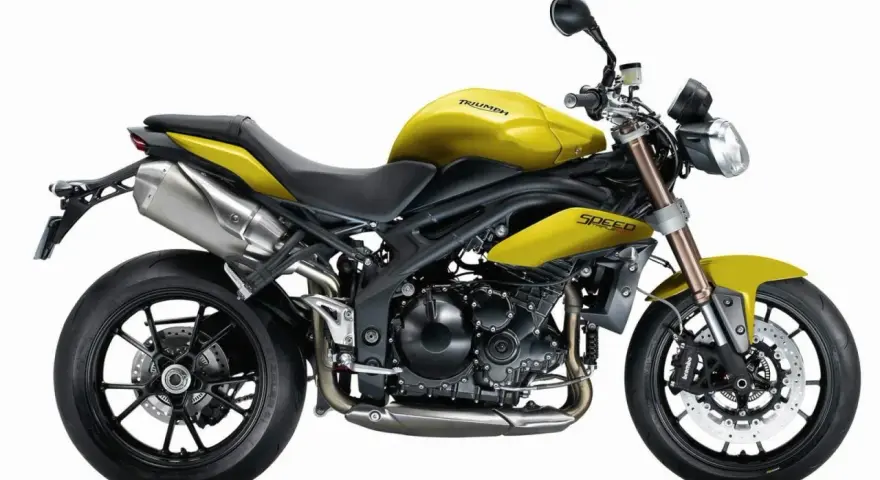 Żółty motocykl Triumph Speed Triple 1050 z czarnymi felgami i wydechem.