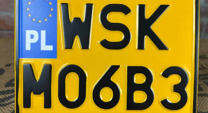 Żółta tablica rejestracyjna z oznaczeniem PL i numerem WSK M06B3.