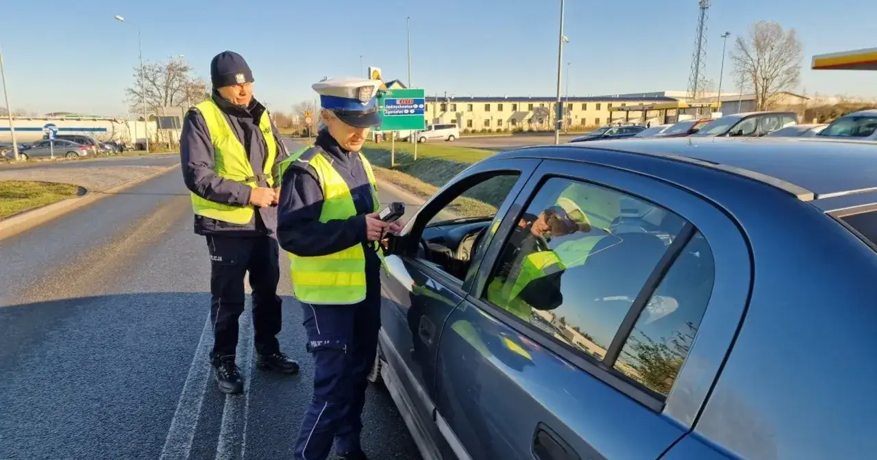 Policjanci kontrolują kierowcę, który nie ma przy sobie prawa jazdy. Sprawdzają, ile mandatu za brak prawa jazdy może otrzymać.