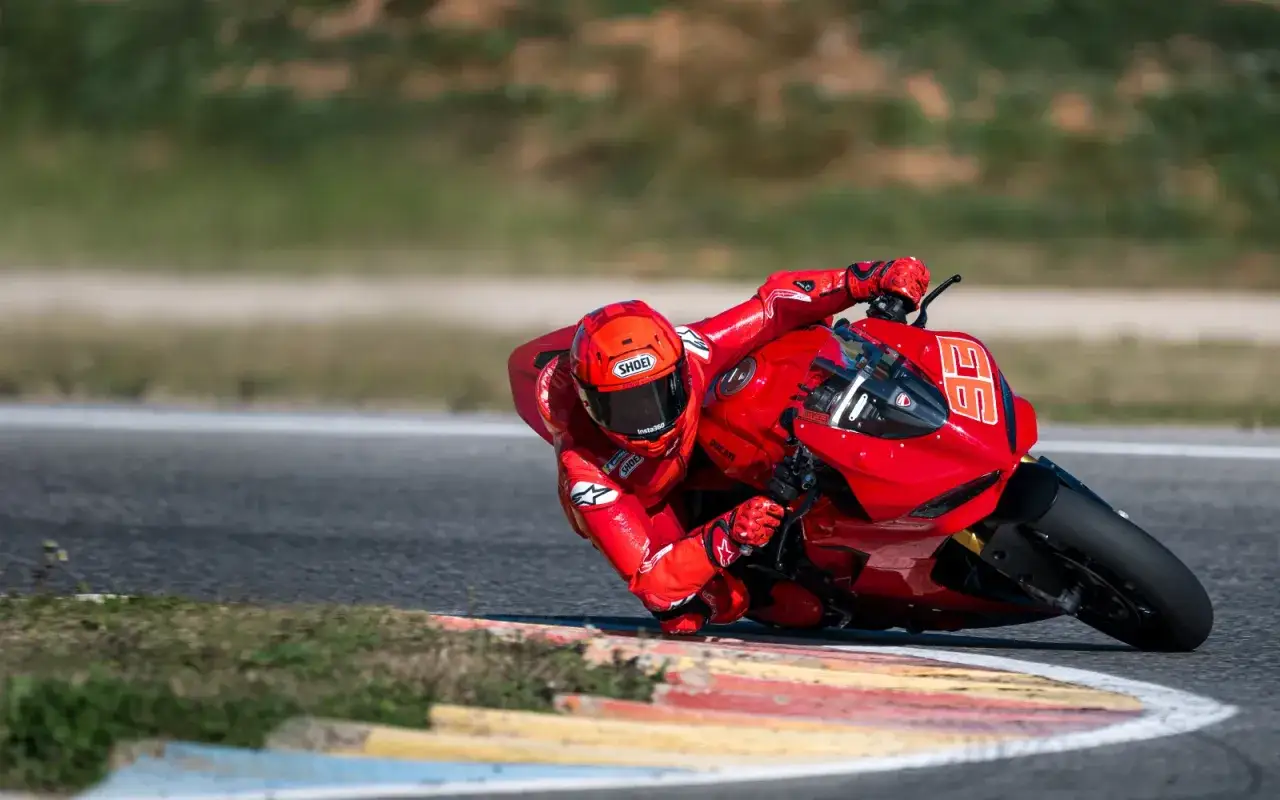 Motocyklista w czerwonym kombinezonie pochyla się na torze wyścigowym na swoim czerwonym motocyklu Panigale V2, z numerem 36.