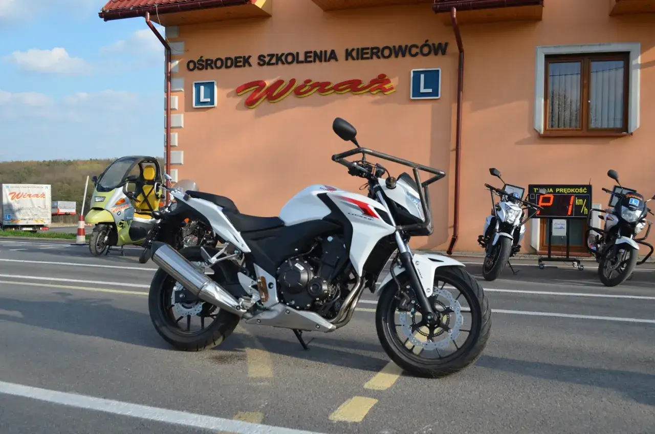 Biały motocykl przed ośrodkiem szkolenia kierowców 
