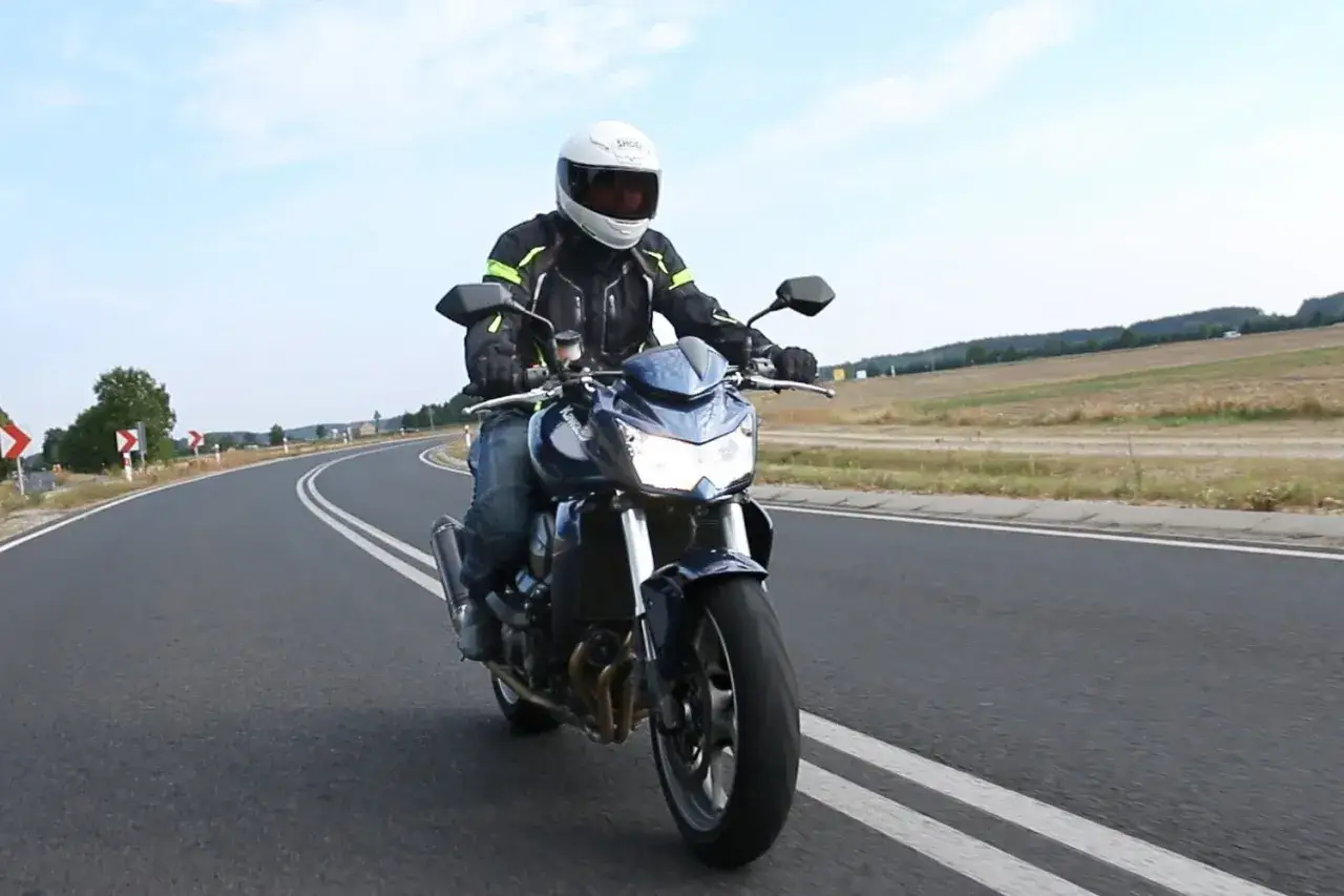 Motocyklista na Kawasaki Z750, sprawdza dane techniczne podczas jazdy po krętej drodze.