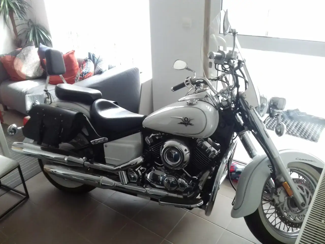 Biały motocykl Yamaha Drag Star 650, z sakwami i wygodnym siedzeniem. Idealny na długie trasy, choć ma swoje wady i zalety.