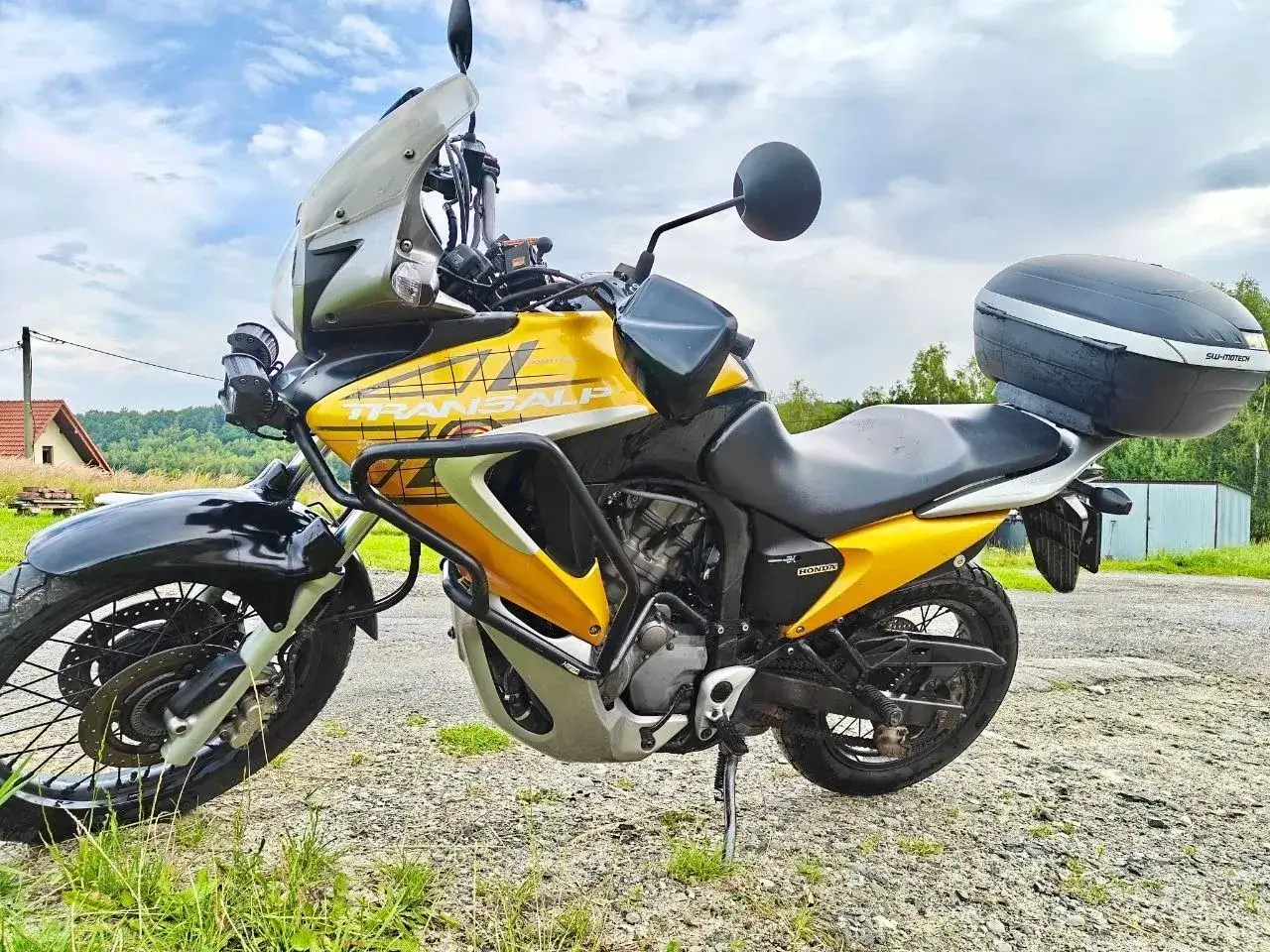 Żółty motocykl Honda Transalp 700, gotowy na przygodę. Dane techniczne tego modelu sprawiają, że jest idealny na długie trasy.