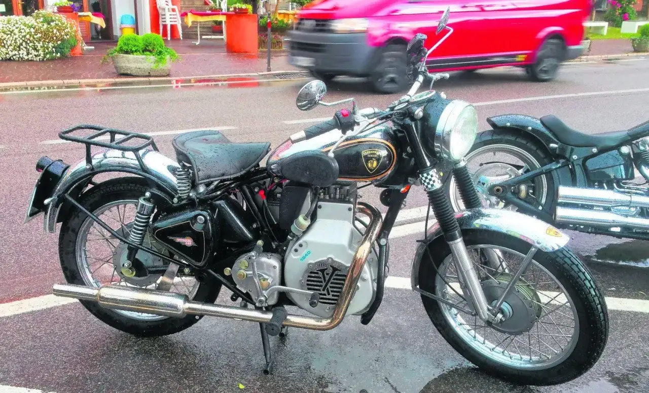 Klasyczny motocykl Royal Enfield Diesel, czarny, z chromowanymi elementami, stoi na mokrej ulicy.