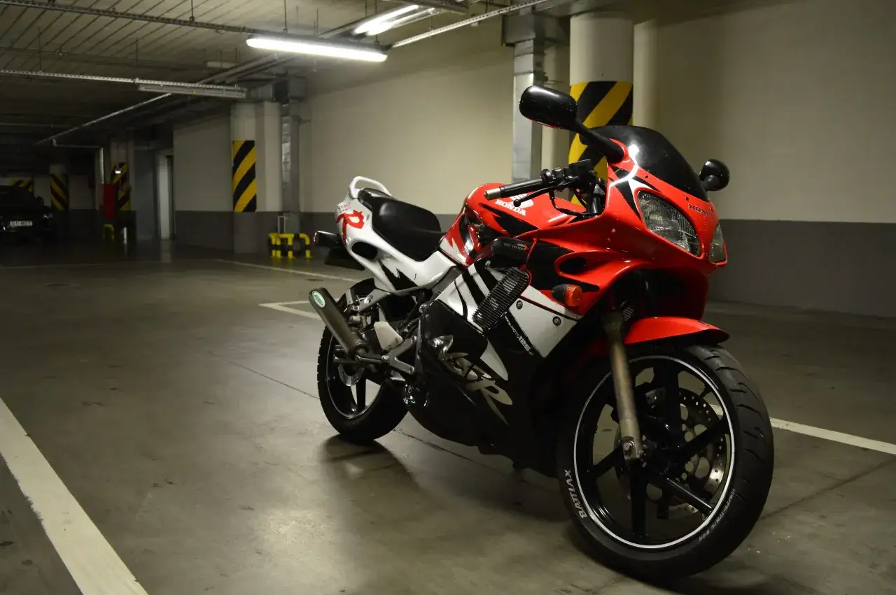 Czerwona Honda NSR 125 V Max, gotowa do jazdy, zaparkowana w garażu.