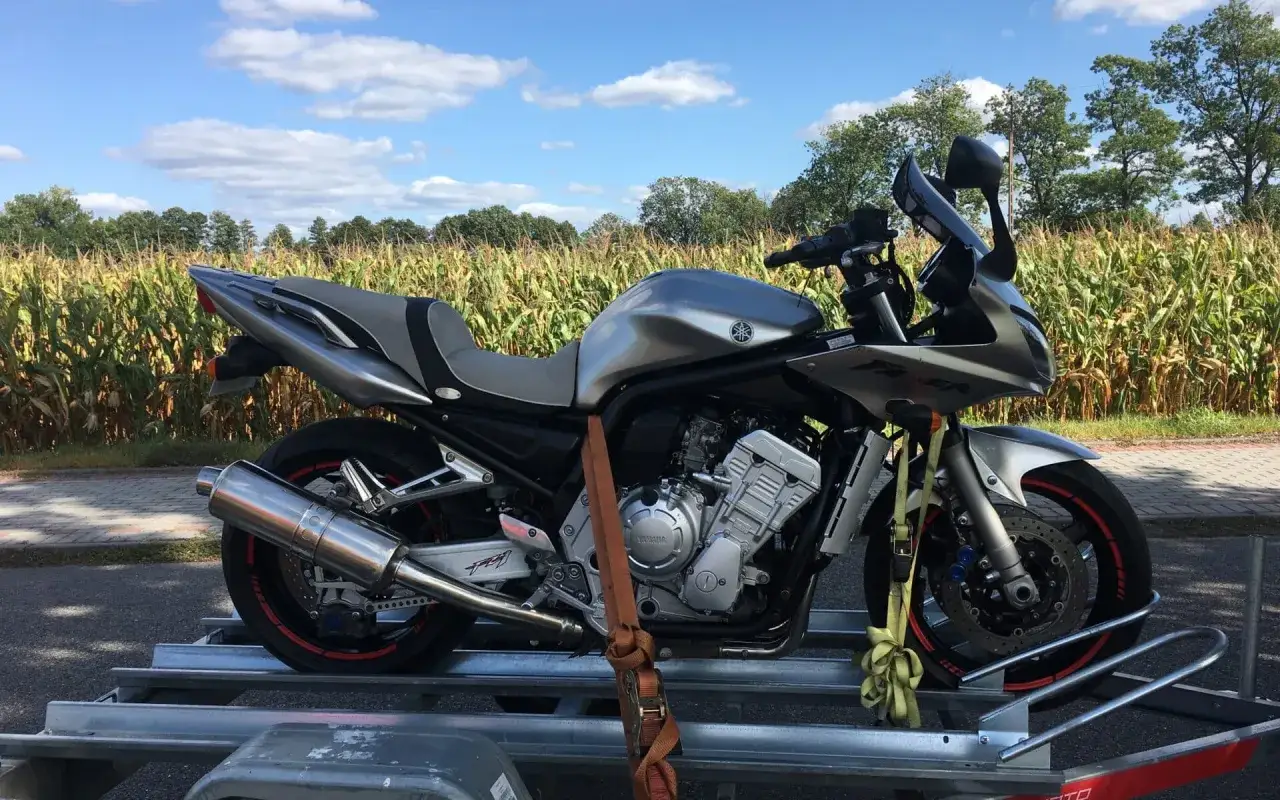 Srebrny motocykl Yamaha na przyczepce, gotowy do transportu. Idealna okazja na tanie motocykle z Niemiec.