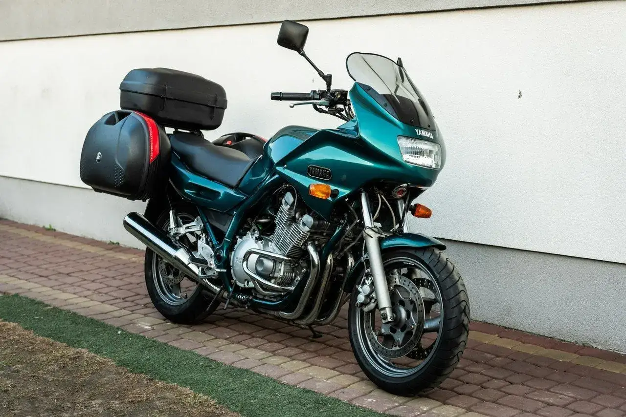 Zielony motocykl Yamaha XJ 900 z kuframi, gotowy na podróż.
