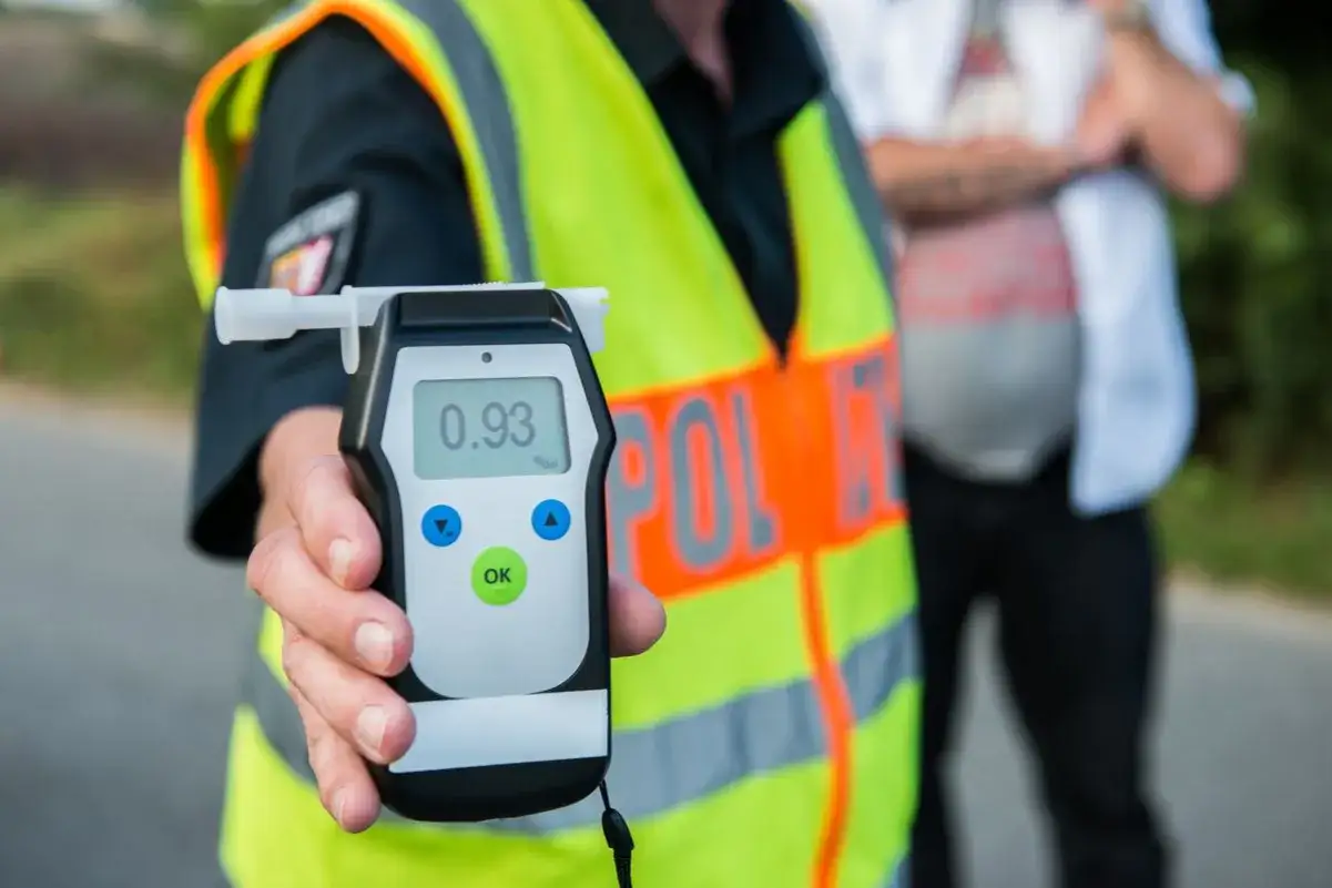 Policjant pokazuje alkomat z wynikiem 0.93 promila. To przekroczenie dopuszczalnej ilości alkoholu w wydychanym powietrzu.