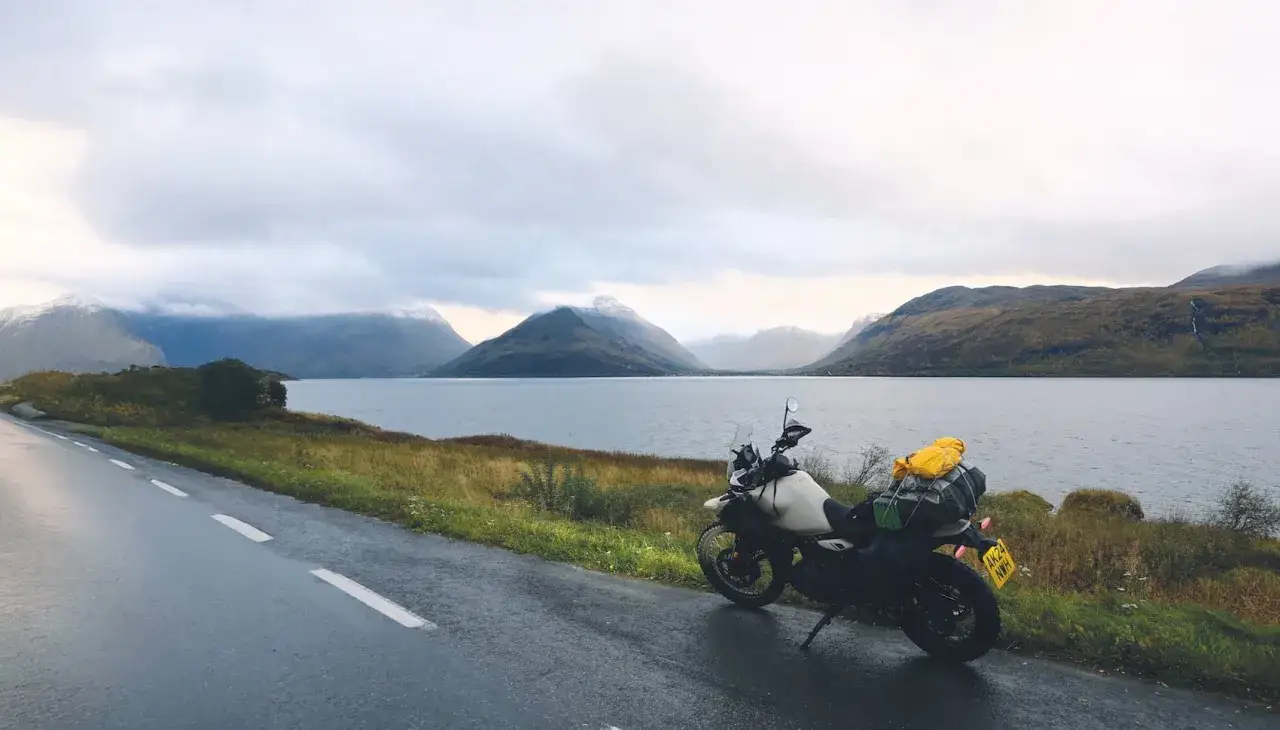 Motocykl zaparkowany nad jeziorem, w tle góry. Droga do Nordkappu, podróż życia.