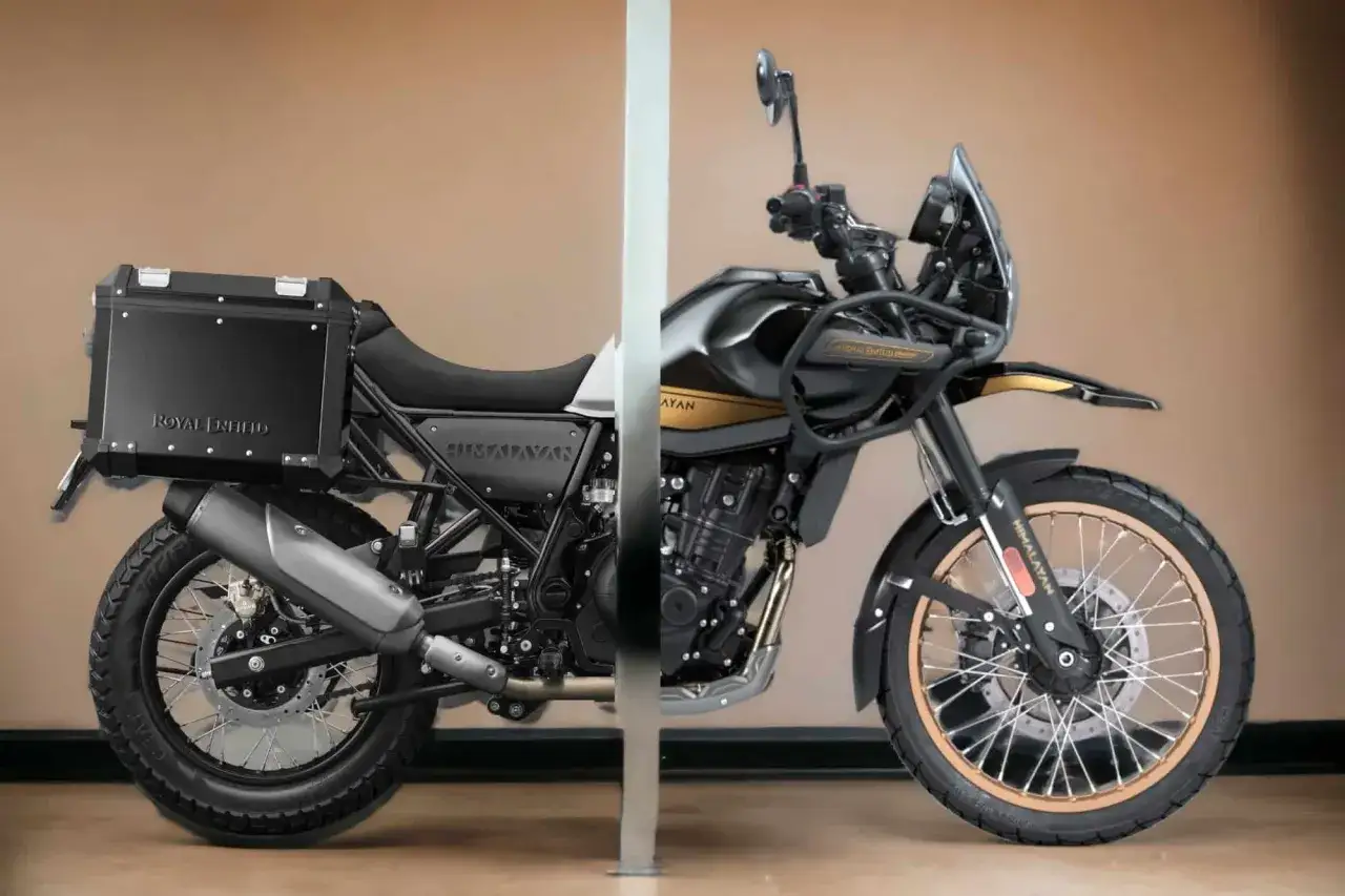 Czarny Royal Enfield Himalayan z kufrem i złotymi akcentami, gotowy na przygodę.