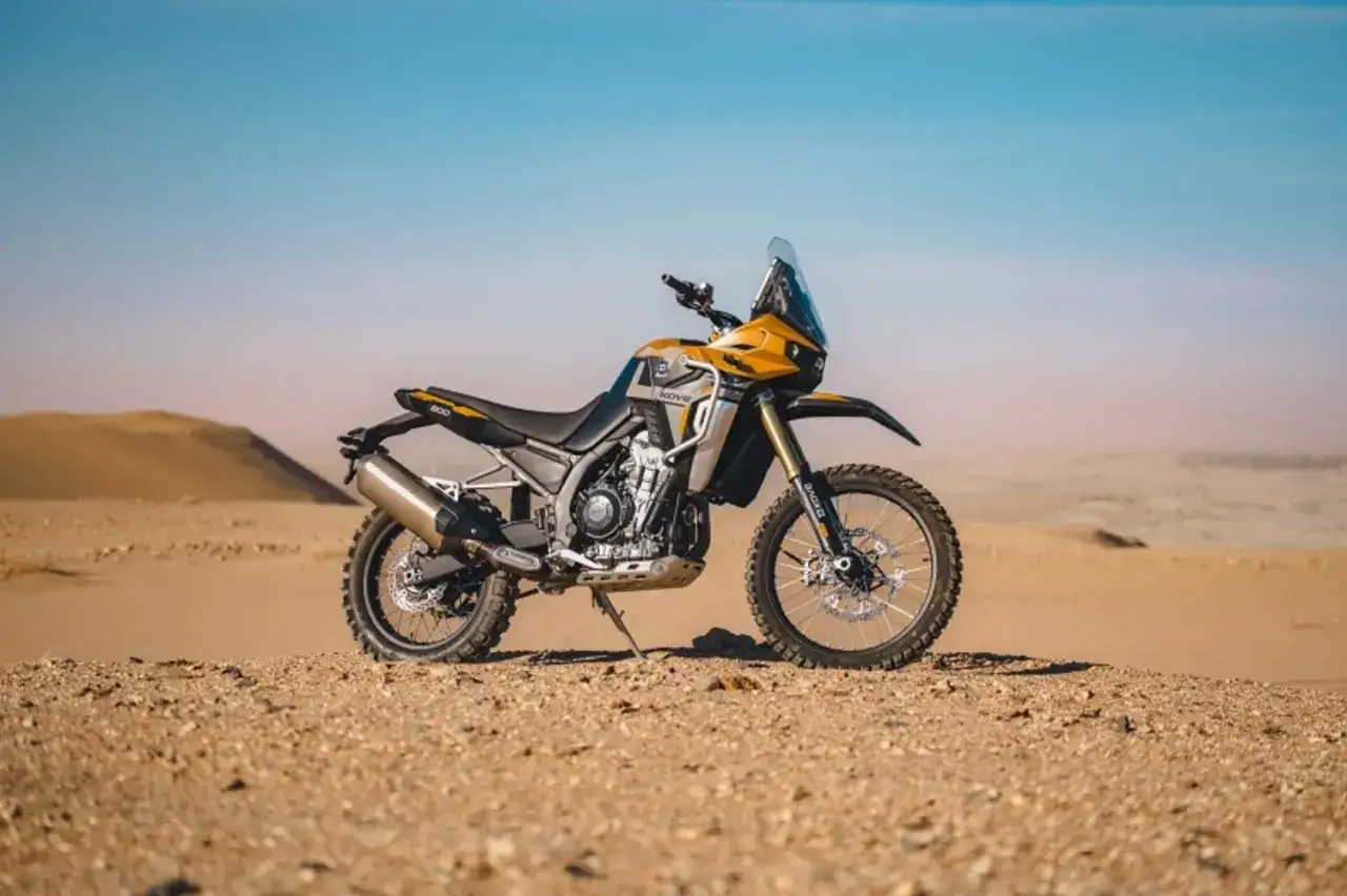 Żółto-czarny motocykl Kove 800x rally na pustynnym tle. Gotowy na rajd przez piaski.