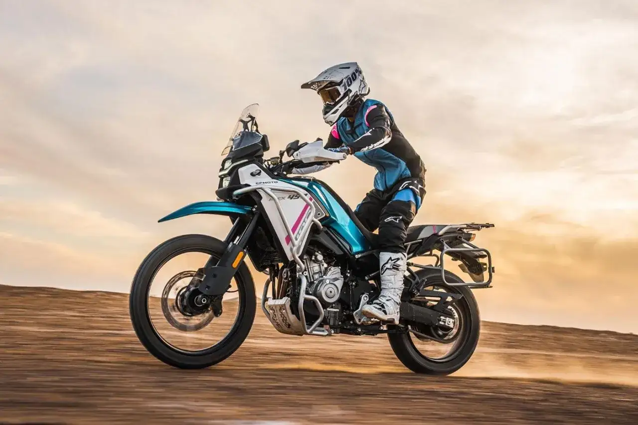 Motocyklista na ekonomicznym motocyklu turystycznym przemierza pustynny krajobraz.