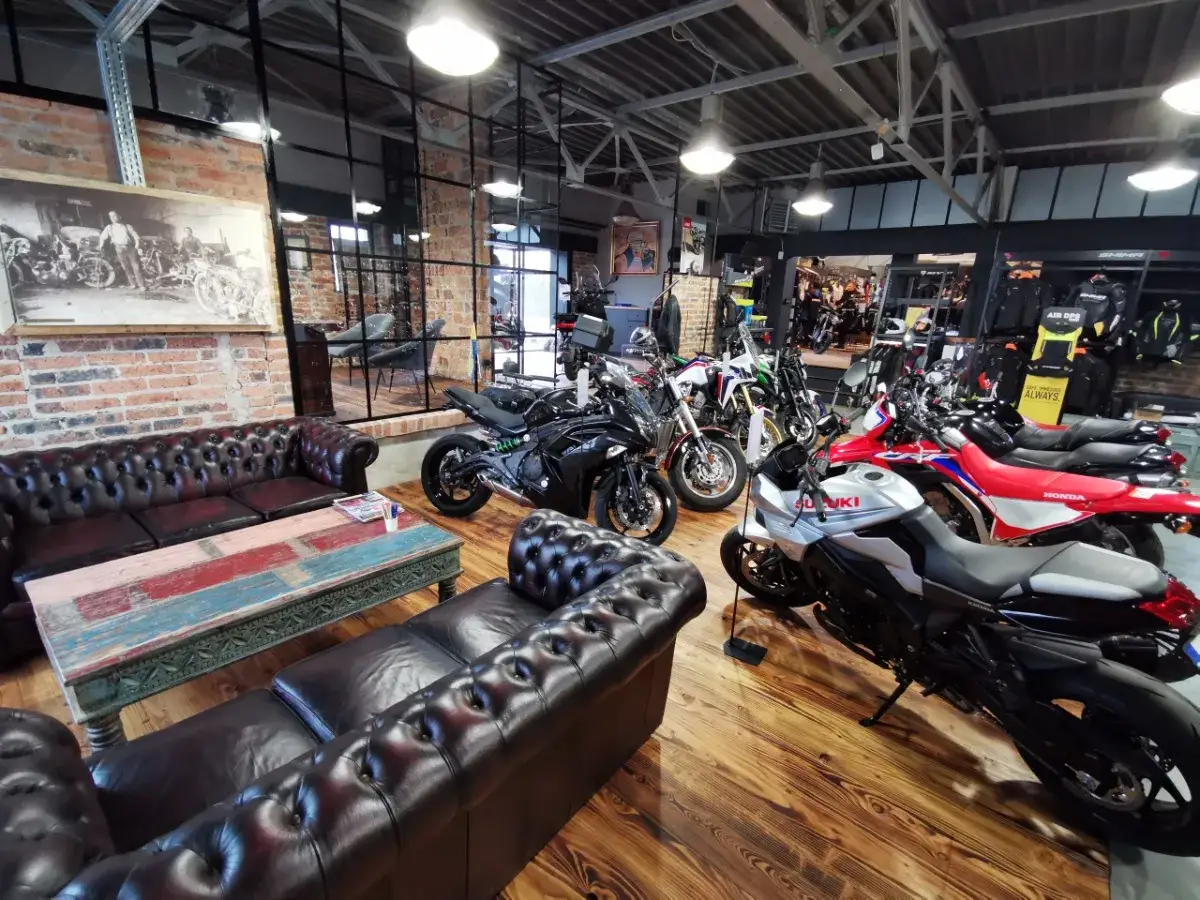 Salon motocyklowy z kanapami i różnymi marki motocykli, w tym Suzuki, Honda i Kawasaki.