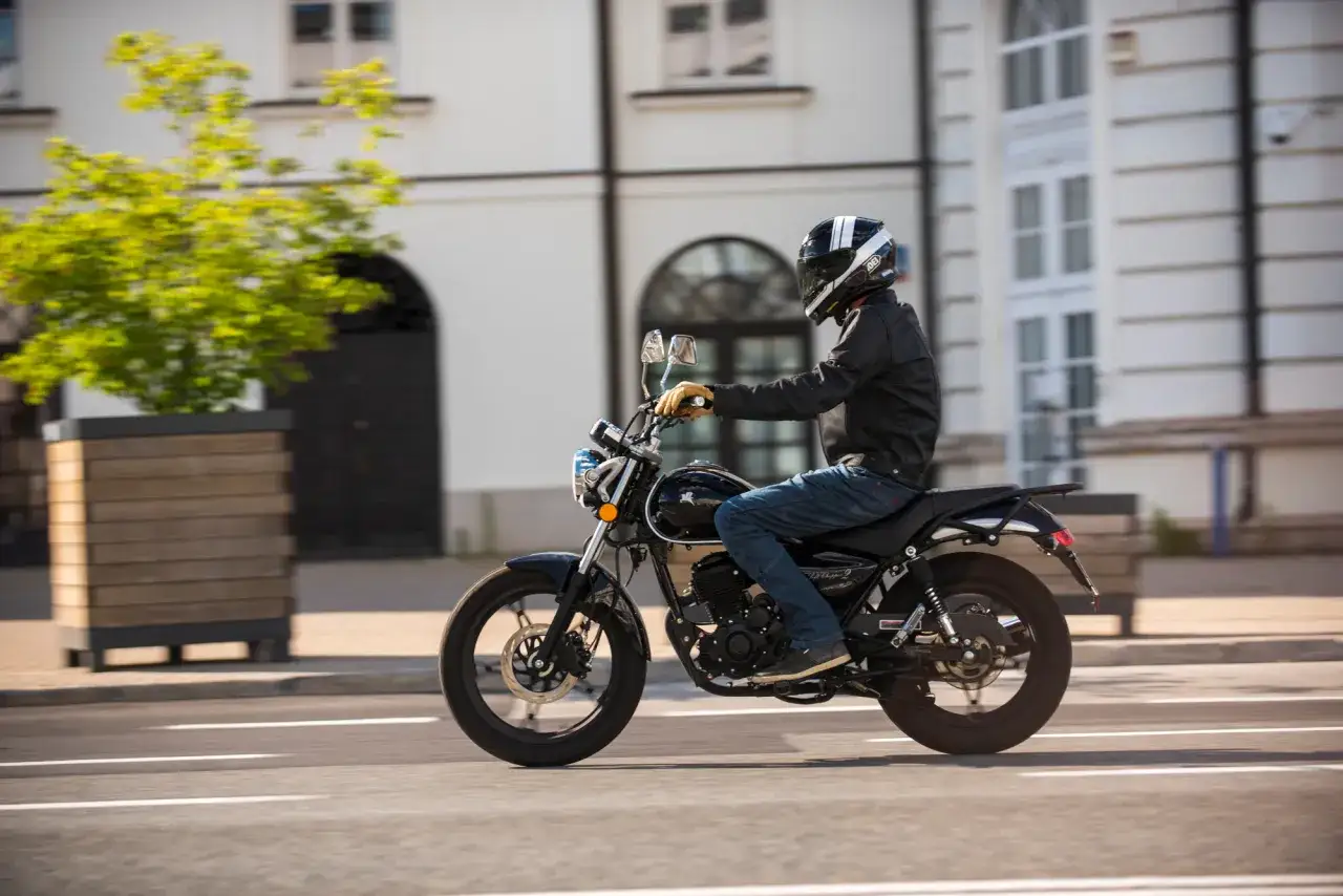 Mężczyzna w kasku jedzie na motocyklu Romet Soft Chopper 125. Poznaj romet soft chopper 125 dane techniczne i poczuj wolność.