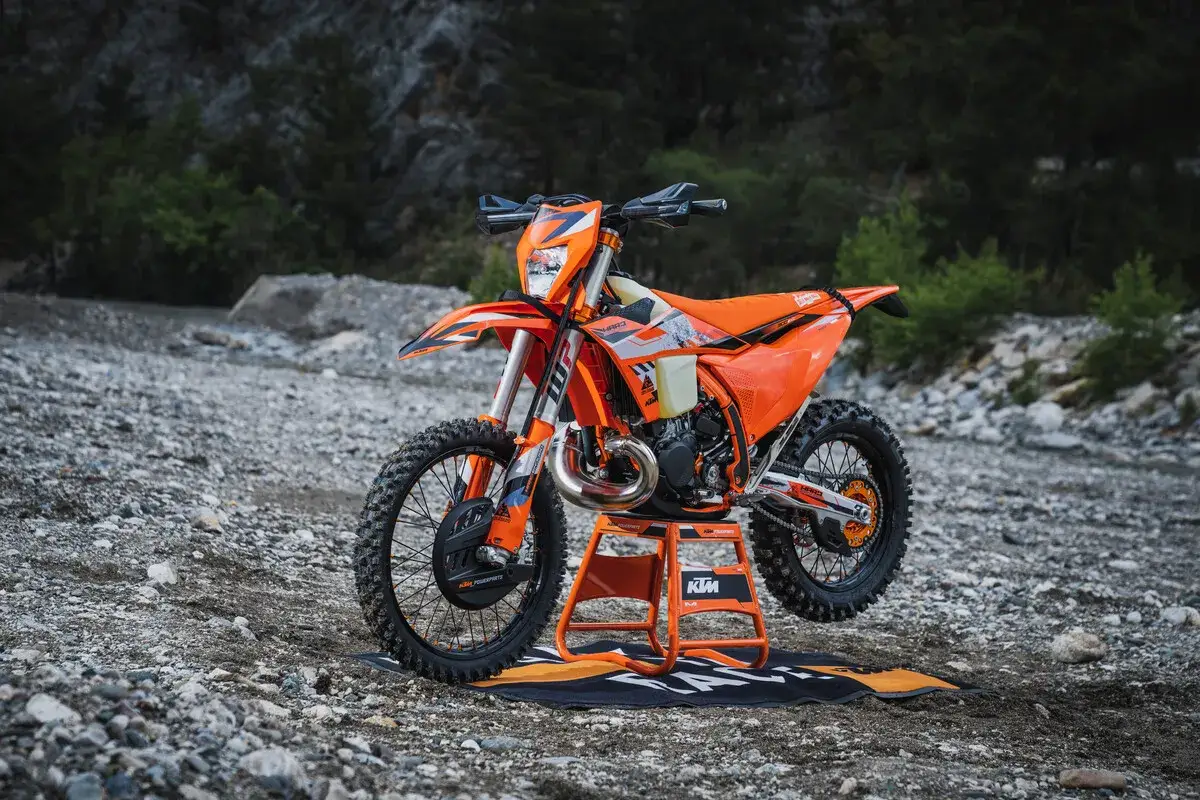 Pomarańczowy KTM EXC 300 2T na stojaku, gotowy do jazdy w terenie. Poznaj jego dane techniczne!