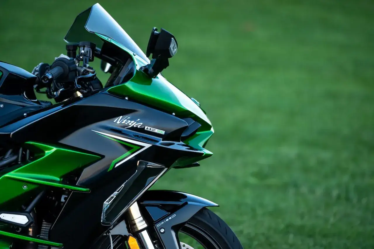 Błyszczący, czarno-zielony motocykl Kawasaki H2 SX na tle trawy.