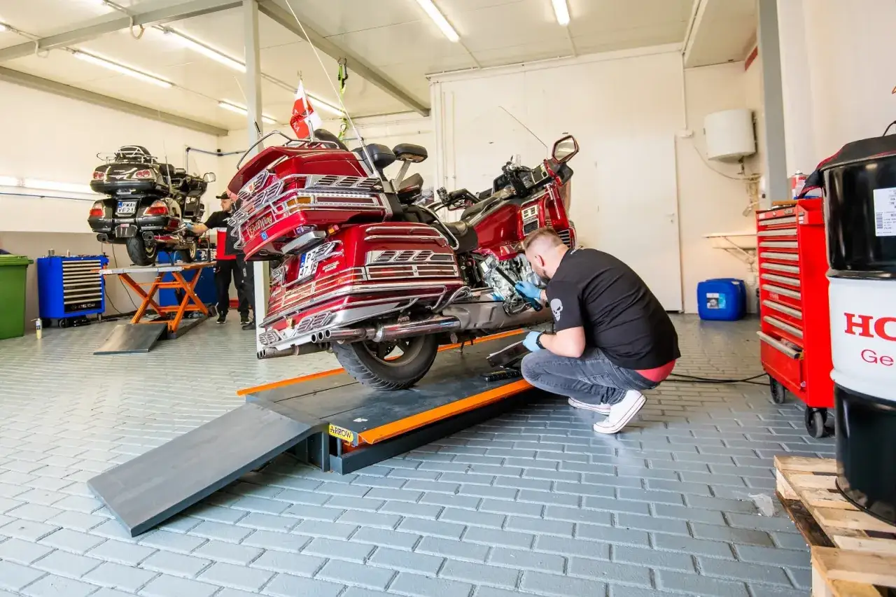 Mechanik sprawdza moc silnika w czerwonym motocyklu na podnośniku.