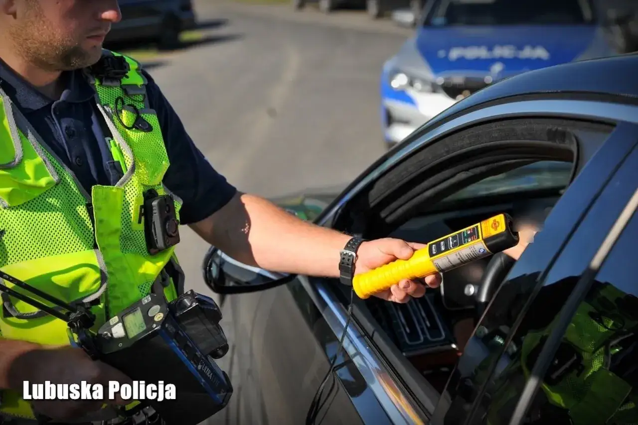 Policjant z Lubuskiej Policji bada kierowcę alkomatem. Pamiętaj, że za jazdę po alkoholu, nawet poniżej 1 promila, grozi utrata prawa jazdy.