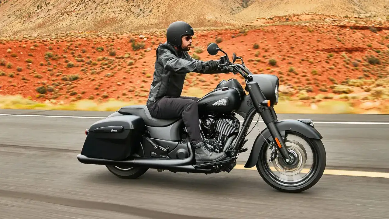 Mężczyzna w kasku i skórzanej kurtce jedzie na czarnym motocyklu Indian. To klasyczne amerykańskie motocykle, idealne na podróż przez pustynne krajobrazy.