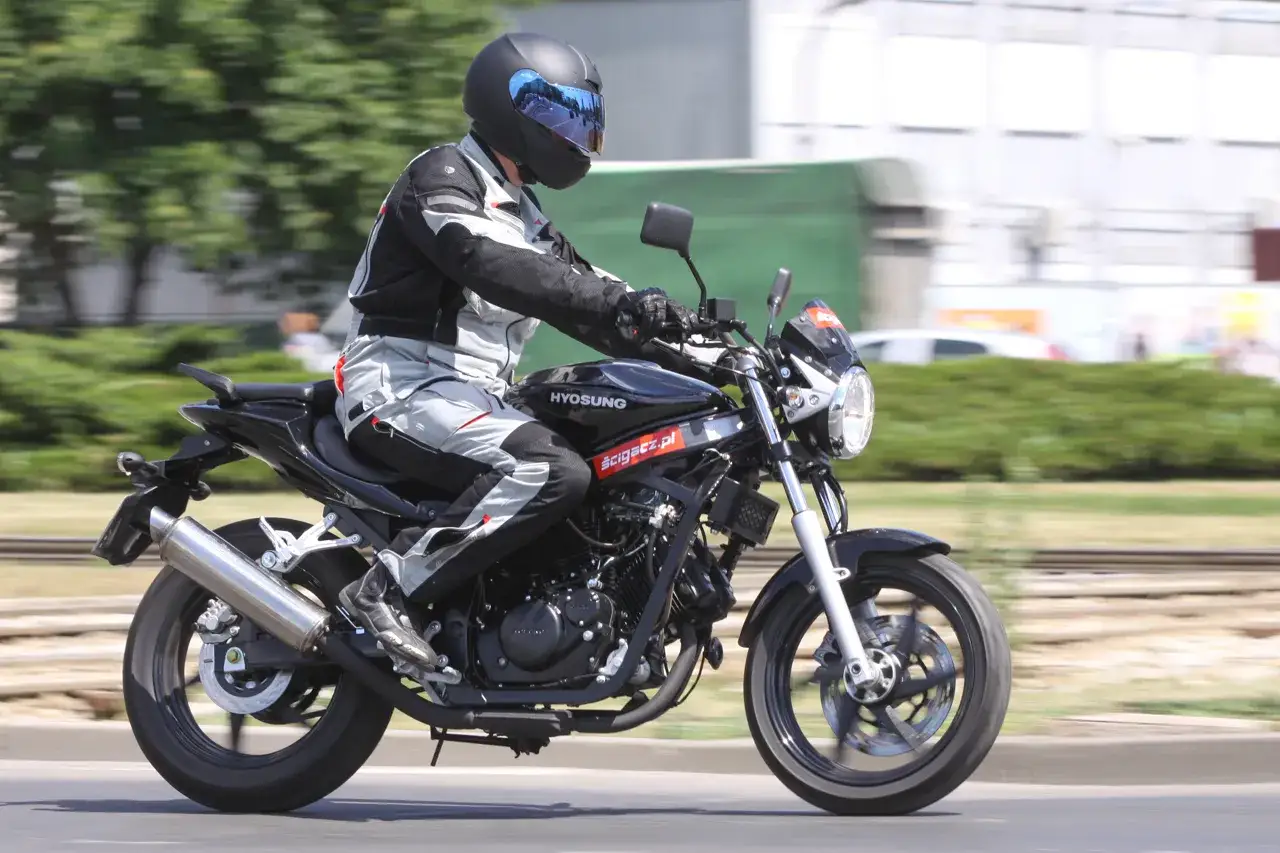 Motocyklista w kasku i stroju jedzie na czarnym Hyosung GT 125.