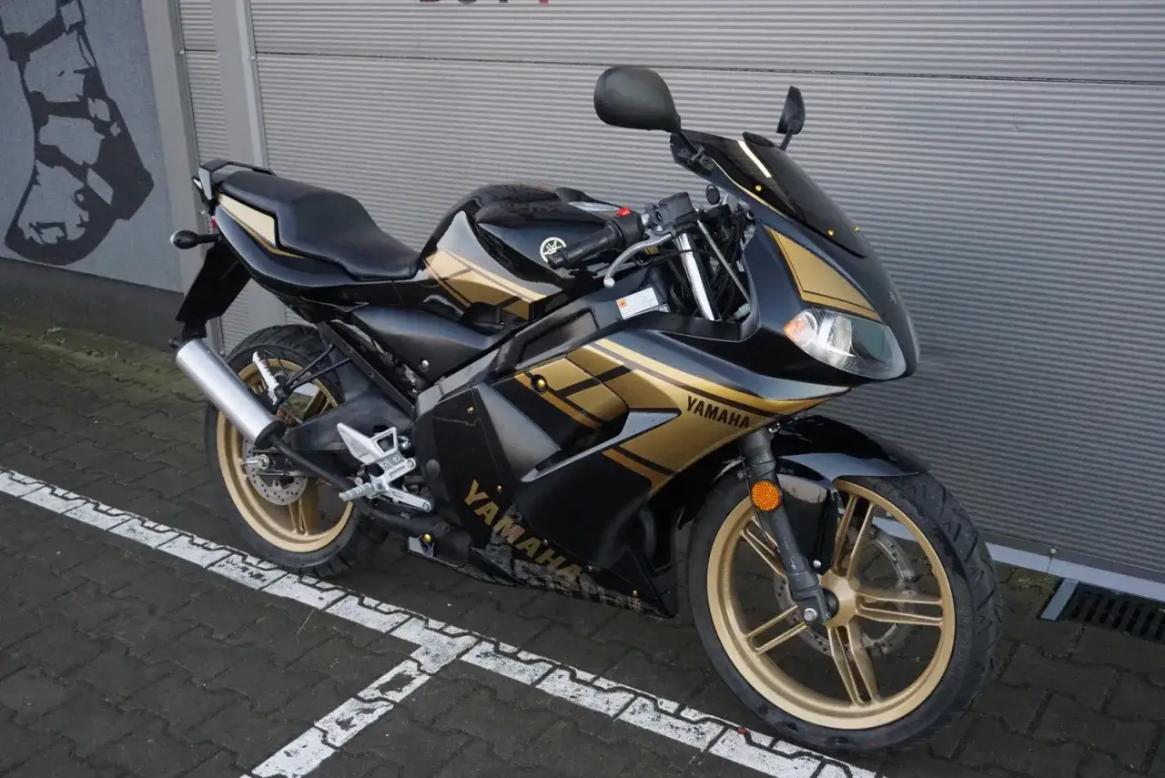 Czarny motocykl Yamaha TZR 50 z złotymi akcentami, idealny na pierwsze wrażenia z jazdy. Sprawdź jego atrakcyjną yamaha tzr 50 cena!