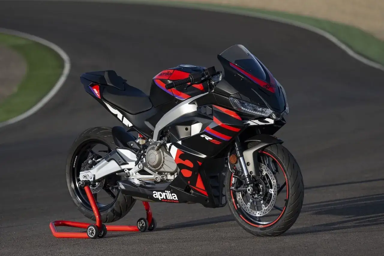 Czarny motocykl Aprilia RS 660 z czerwonymi i niebieskimi akcentami, gotowy do jazdy na torze. Silnik o mocy 35 kw.
