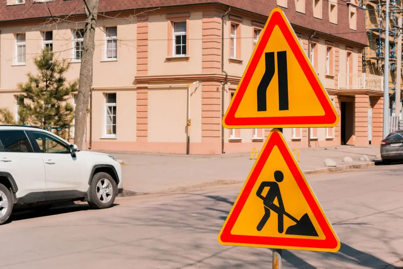 Znaki drogowe ostrzegają o zwężeniu jezdni i robotach drogowych. Kierowcy muszą ustąpić pierwszeństwa na zwężonym odcinku jezdni.