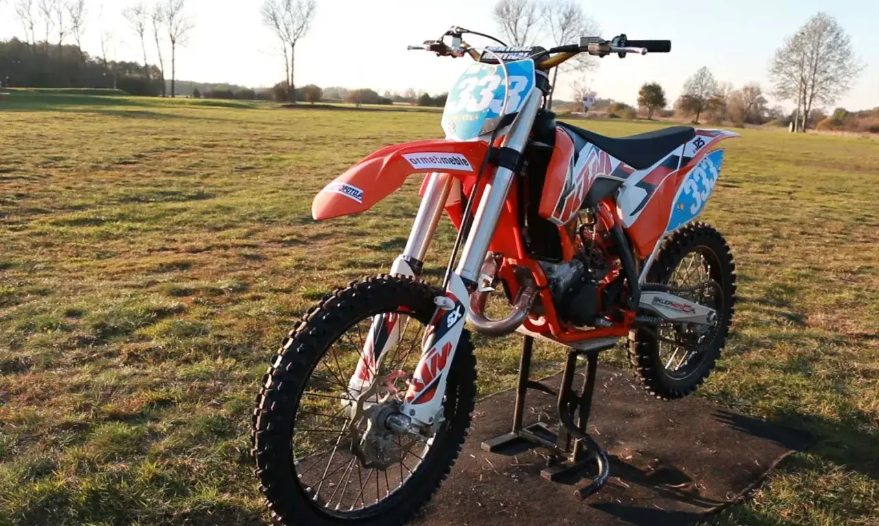 Pomarańczowy KTM SX 125 na stojaku, gotowy do akcji. Czy wiesz, ile koni ma KTM SX 125? To potężna maszyna!