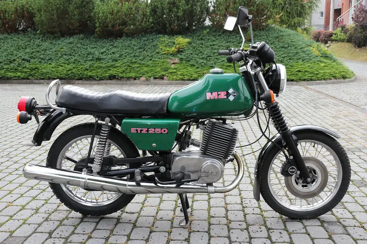 Zielony motocykl MZ ETZ 250 z lat 80. stoi na brukowanym podjeździe.