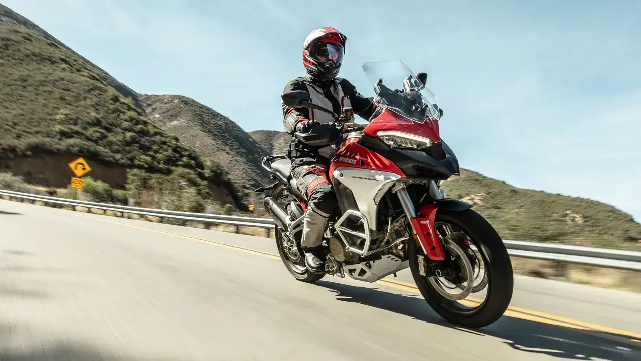 Motocyklista na czerwonym Ducati jedzie krętą drogą w górach. Czy do Włoch potrzebny jest paszport? Z pewnością warto go mieć, jeśli planujesz taką podróż!