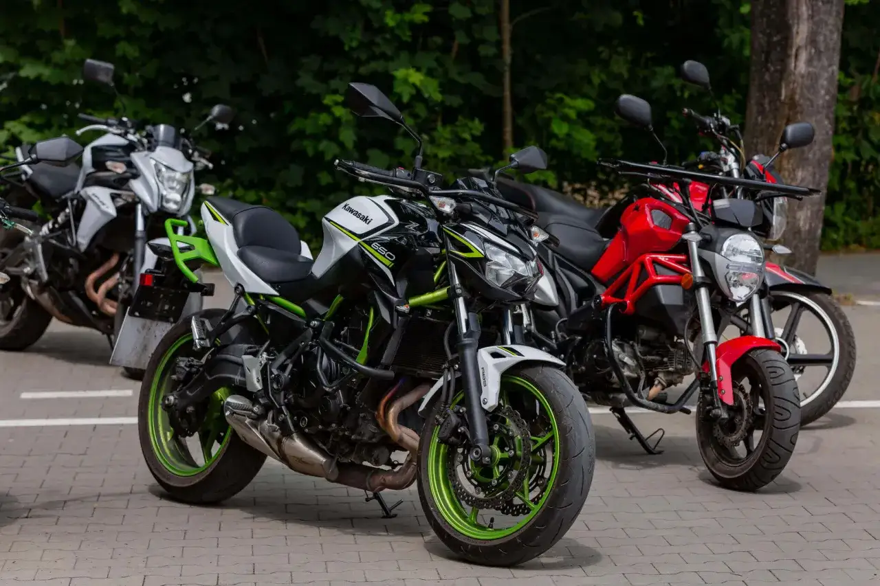Trzy motocykle: biało-czarny Kawasaki z zielonymi akcentami (model Z650, a2 motor), czerwony i biały.