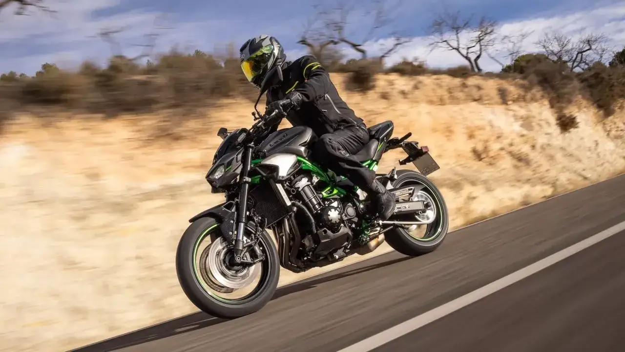 Motocyklista w kasku pędzi na Kawasaki Z900 po pustynnej drodze.