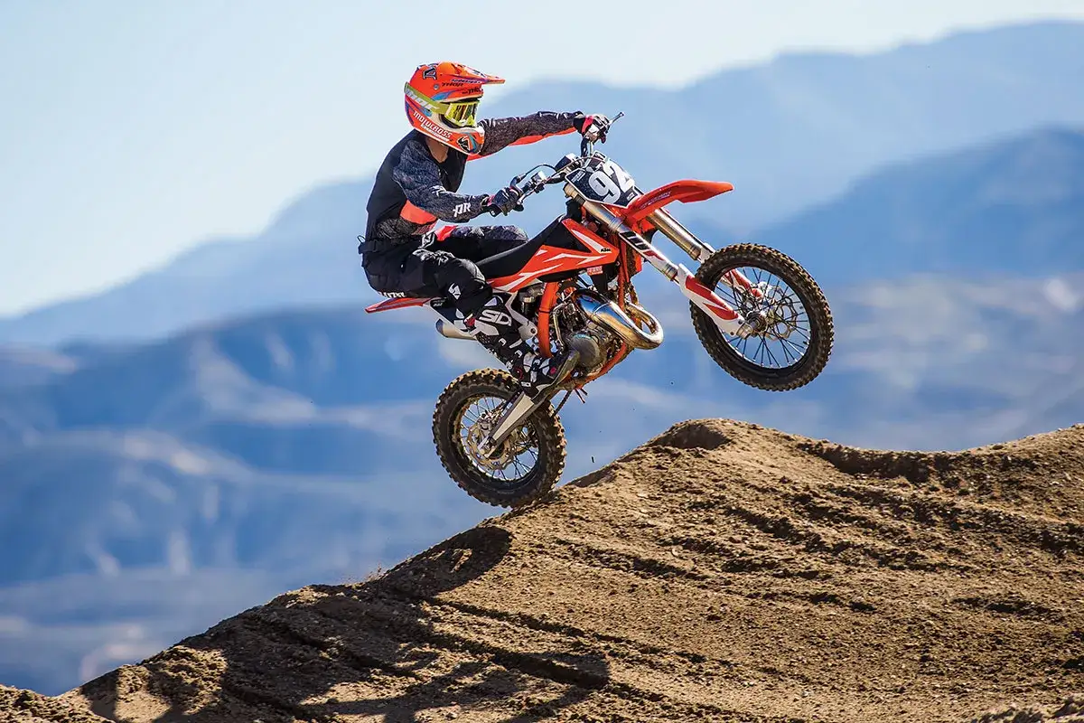 Motocrossowiec na KTM SX 85 w powietrzu, pokonując przeszkodę. Niesamowita prędkość maksymalna w akcji.