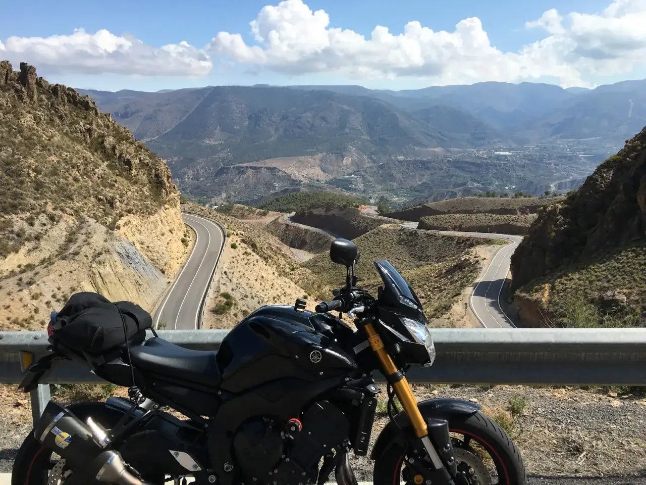 Czarny motocykl Yamaha FZ8 zaparkowany na tle malowniczej, górskiej drogi z serpentynami.