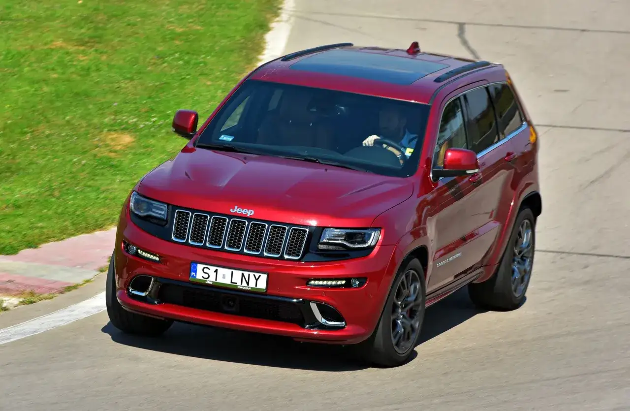 Czerwony Jeep Grand Cherokee na torze. Zastanawiasz się, ile kosztuje personalizowana rejestracja, jak ta 