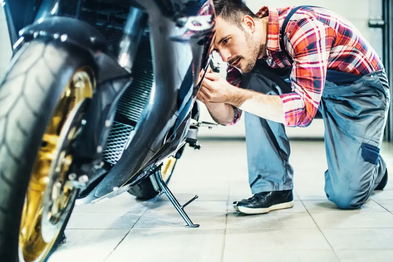 Mechanik sprawdza motocykl, zastanawiając się, ile kosztuje przegląd motocykla.