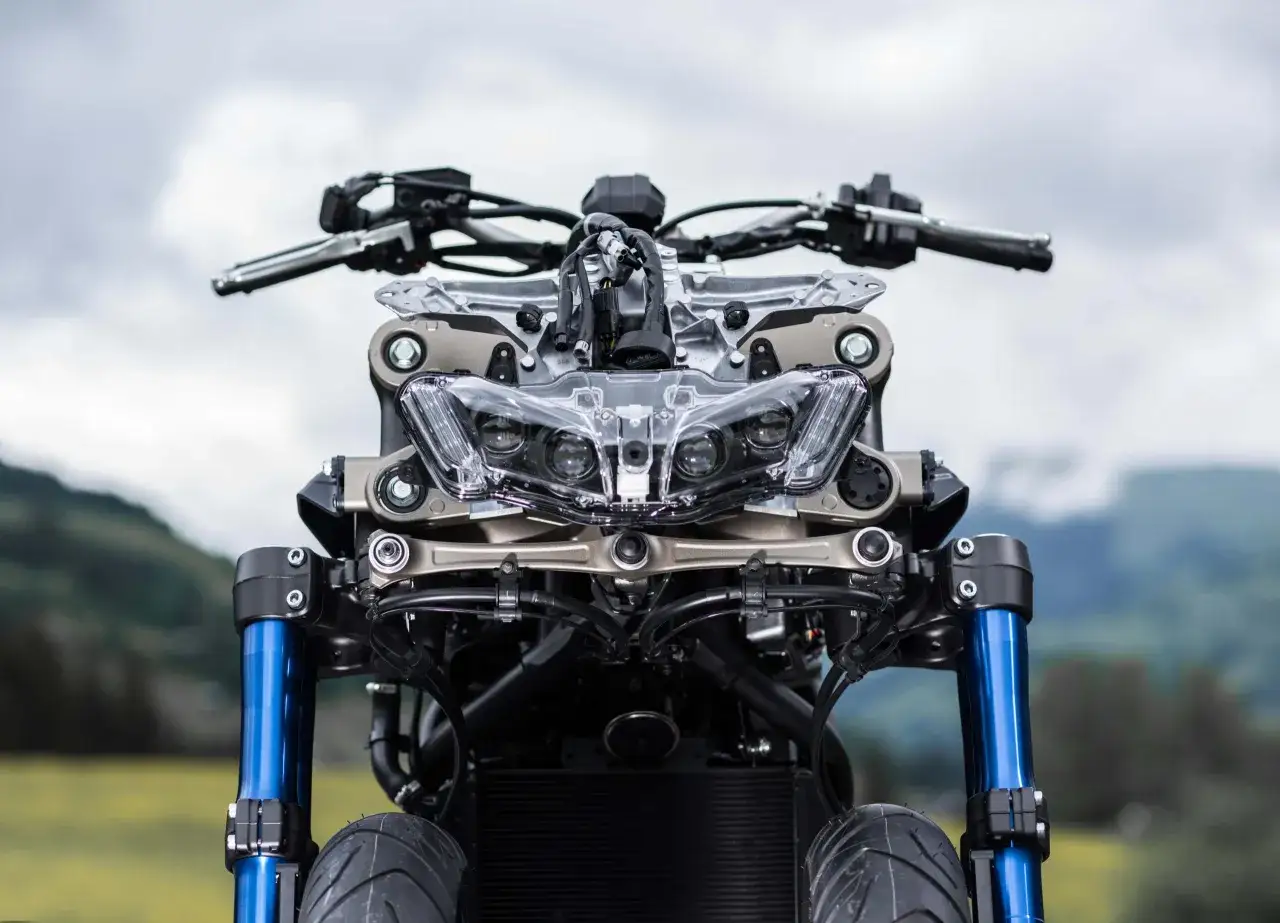 Przód motocykla Yamaha Niken z niebieskimi lagami i charakterystycznym, wielopunktowym reflektorem.
