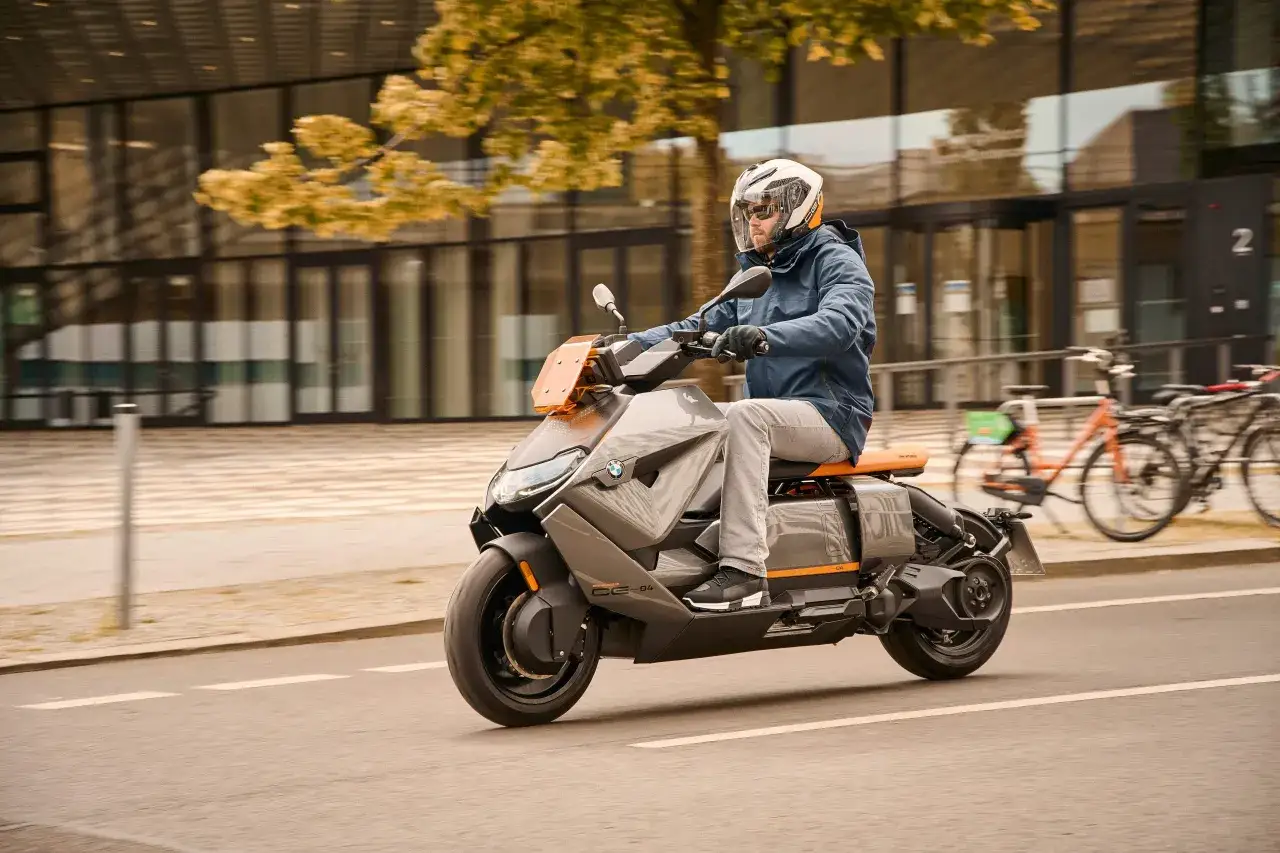 Mężczyzna w kasku jedzie na szarym skuterze BMW CE 04. Zastanawiasz się nad jego bmw ce 04 cena?