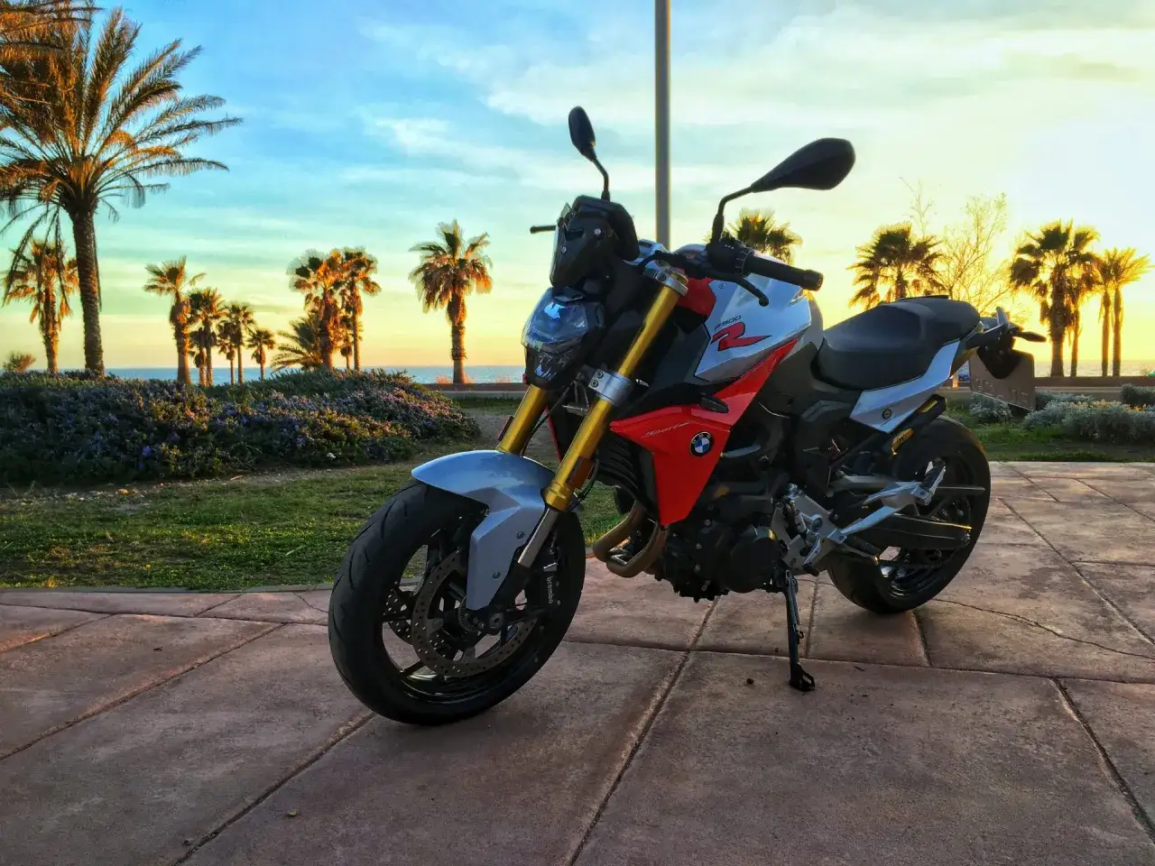 BMW F900R na tle palem i zachodzącego słońca. Idealny motocykl na wakacyjną przejażdżkę.