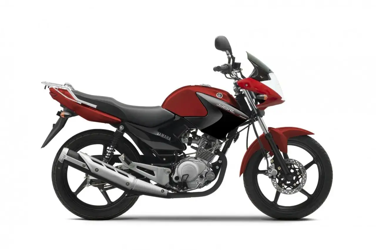Czerwony motocykl Yamaha YBR 125, z czarnymi wstawkami i chromowanym wydechem. Wady tego modelu to m.in. brak ABS.