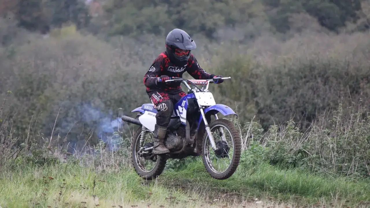 Chłopiec w kasku i stroju motokrosowym skacze na motocyklu Yamaha. Idealny jaki cross dla 14 latka, by poczuć adrenalinę!