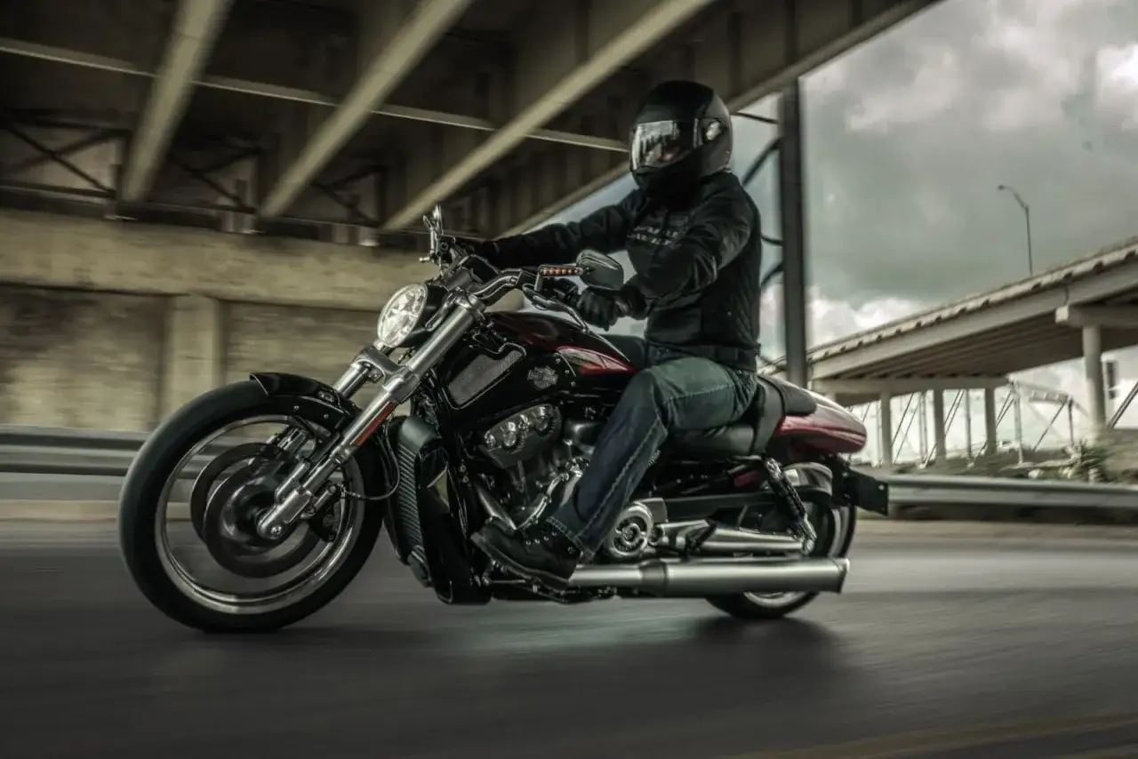 Motocyklista w kasku pędzi na potężnym v-rod muscle pod betonowym wiaduktem.