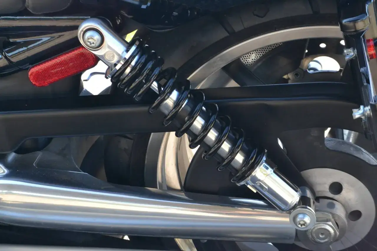 Amortyzator motocykla, błyszczący chrom i czarna sprężyna. Może to być związane z problemami z silnikiem, jak spalanie stukowe.