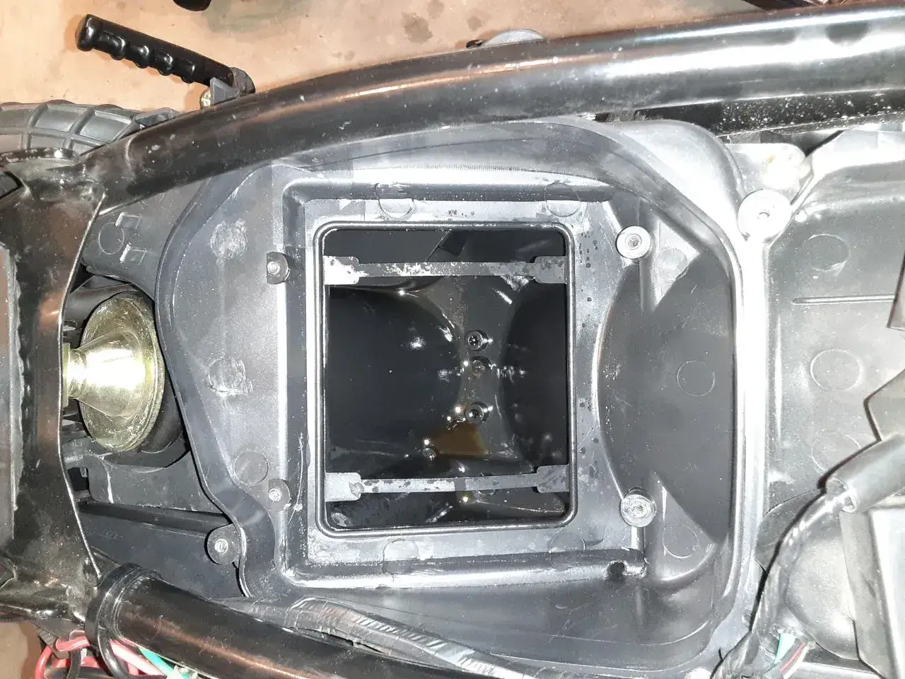 W komorze filtra powietrza motocykla widać ciemny olej.