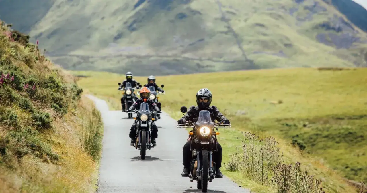 Grupa motocyklistów na angielskich motocyklach przemierza malowniczą, górską drogę.