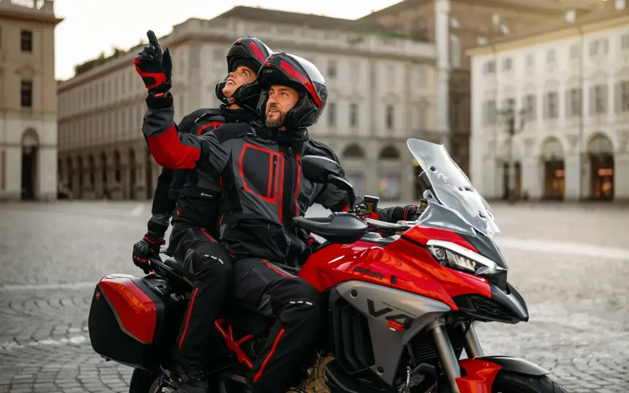 Para na czerwonym Ducati Multistrada w miejskim krajobrazie. Ona wskazuje drogę, on patrzy w tym samym kierunku.
