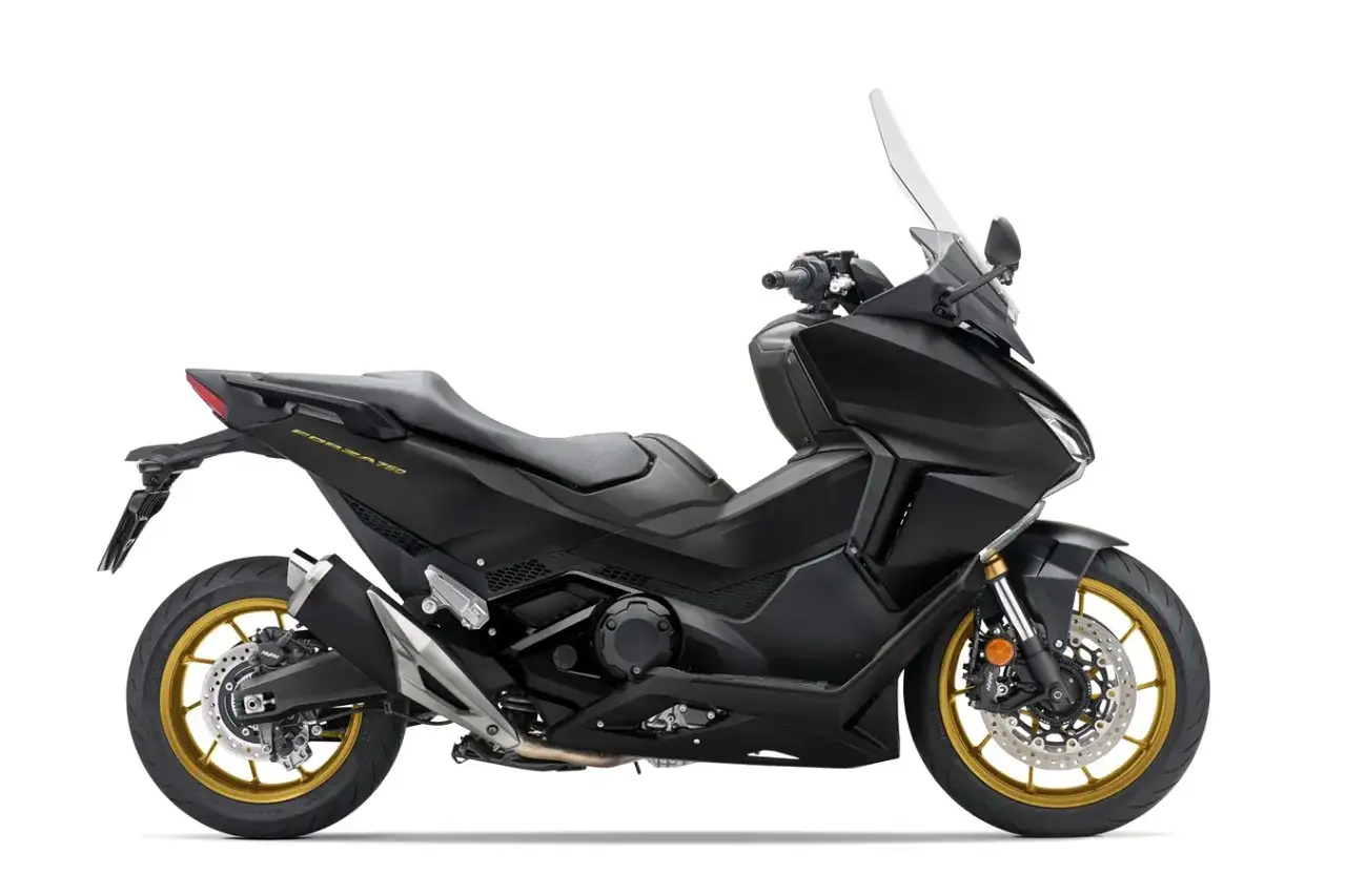 Czarny skuter Honda Forza 750, gotowy do osiągnięcia swojej maksymalnej prędkości. Złote felgi dodają mu sportowego charakteru.