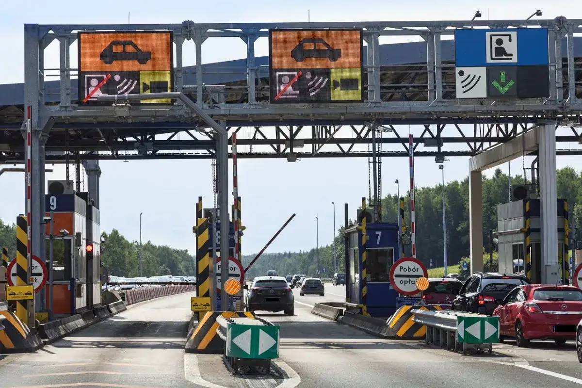 Pobieranie opłat na autostradzie A4. Samochody zbliżają się do bramek, na których wyświetlane są informacje o ruchu.